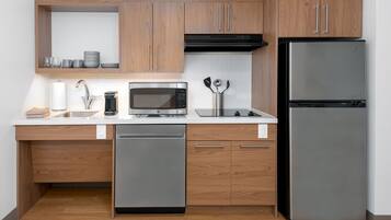 Una cocina moderna con armarios de madera, un refrigerador de acero inoxidable, un microondas y un lavavajillas.