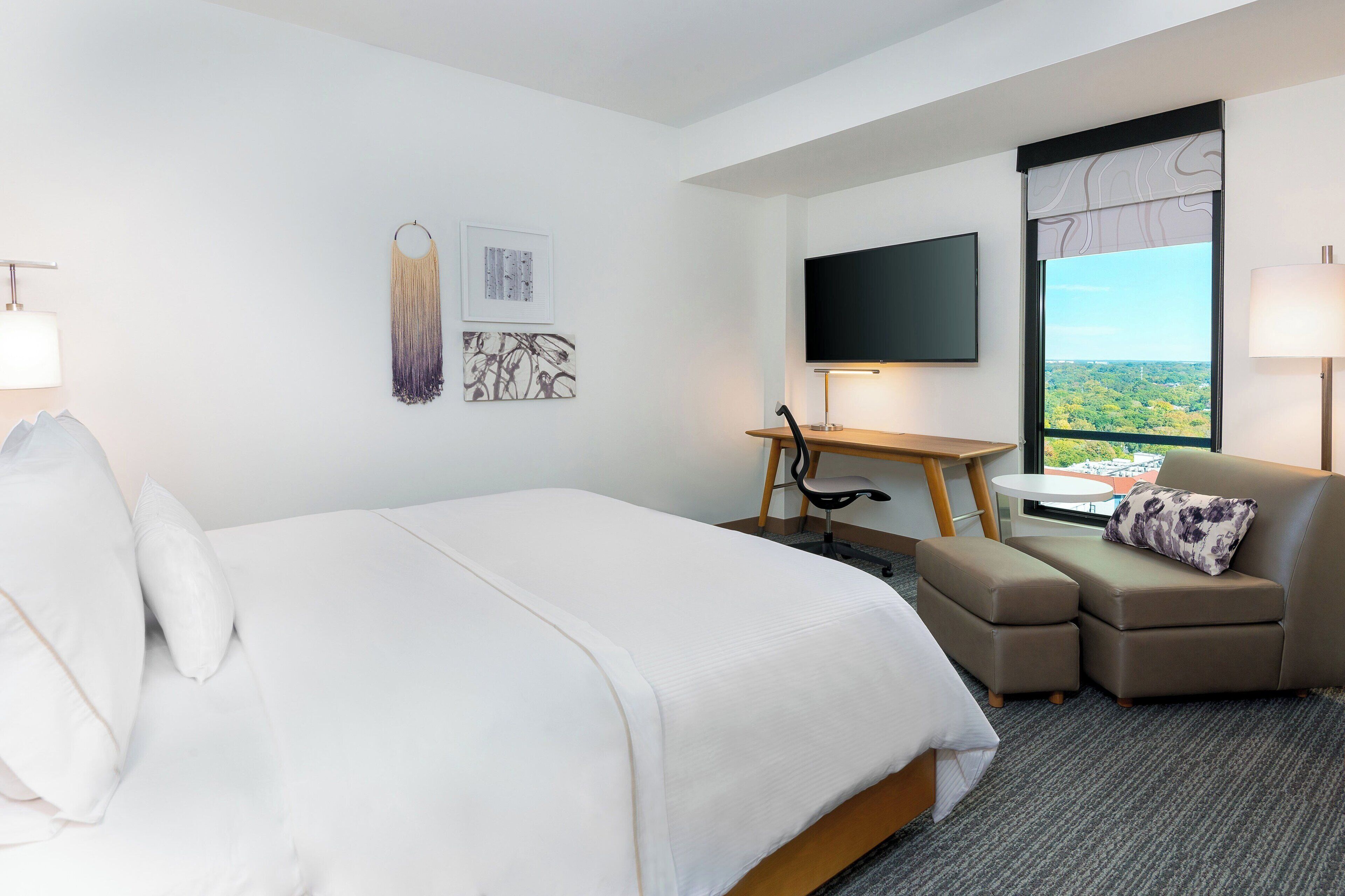 A hotel room with a large bed, a desk, a sofa, and a TV.