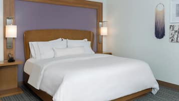 A neatly made bed with white linens, a wooden headboard, and two bedside lamps.