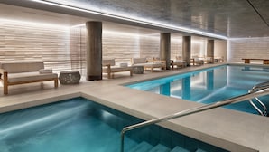 Une piscine intérieure moderne dotée de plusieurs espaces de détente et d’une eau cristalline.