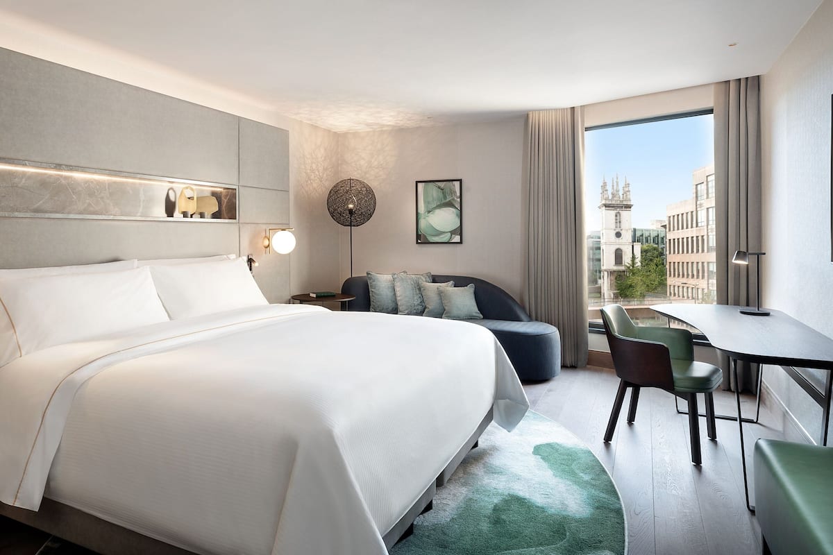 Habitació d'hotel moderna amb un llit gran, zona de seients amb una taula i vistes a la ciutat.