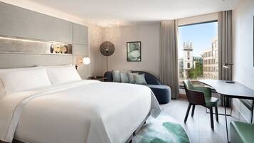Une chambre d’hôtel moderne dotée d’un grand lit, d’un coin salon avec une table et d’une vue sur la ville.