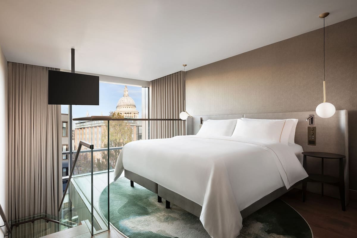 Una habitació d'hotel moderna amb un llit gran, una televisió penjada a la paret i vistes a la ciutat.