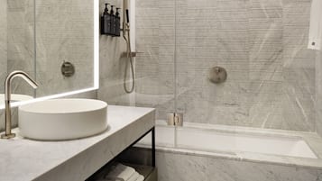 Ein modernes Badezimmer mit einem Marmorwaschbecken, einer Glaskabine zur Dusche und einer Badewanne.