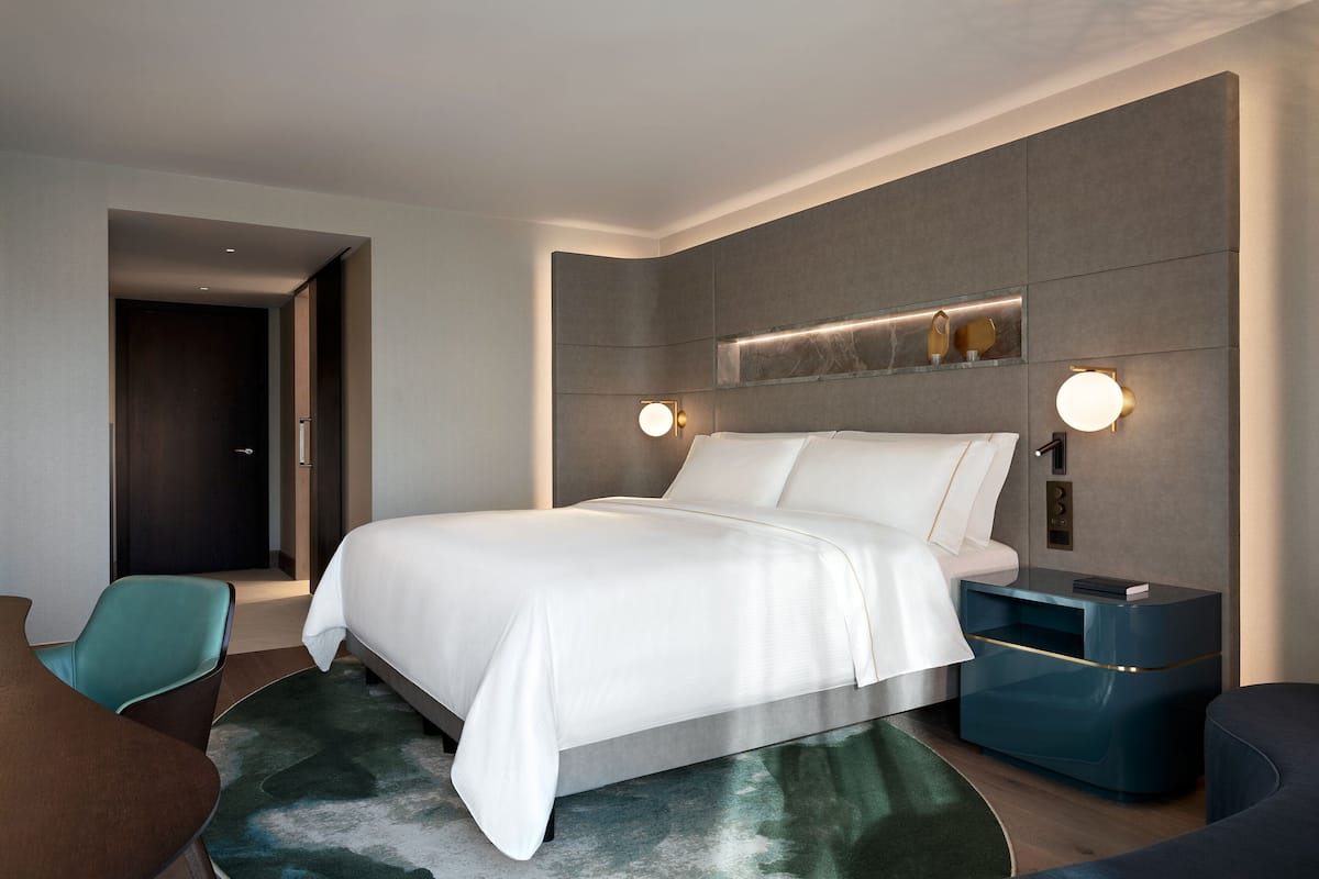 Habitació d'hotel moderna amb un llit gran, una taula de nit, una cadira i un escriptori.