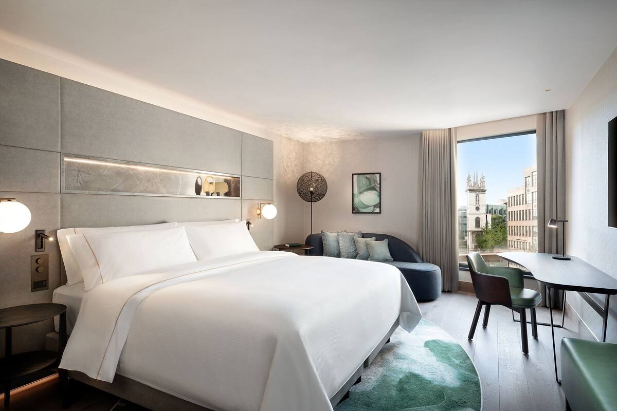 Una habitació d'hotel moderna amb un llit gran, un escriptori i vista a la ciutat.