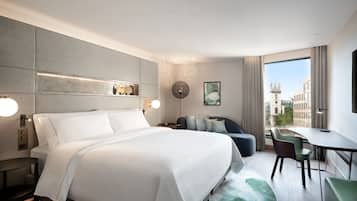 A modern hotel room with a large bed, a desk, and a view of the city.
