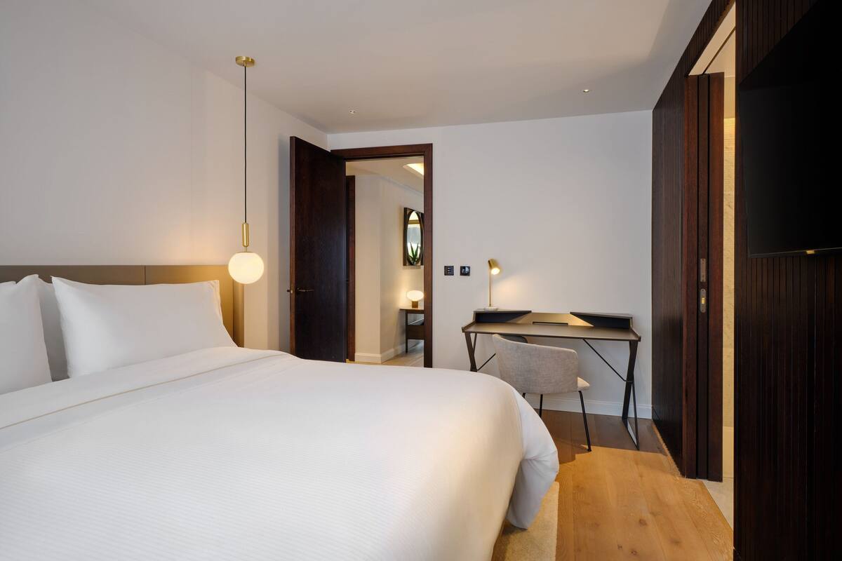 Habitació d'hotel amb un llit gran, escriptori amb cadira, televisió i un armari de fusta.