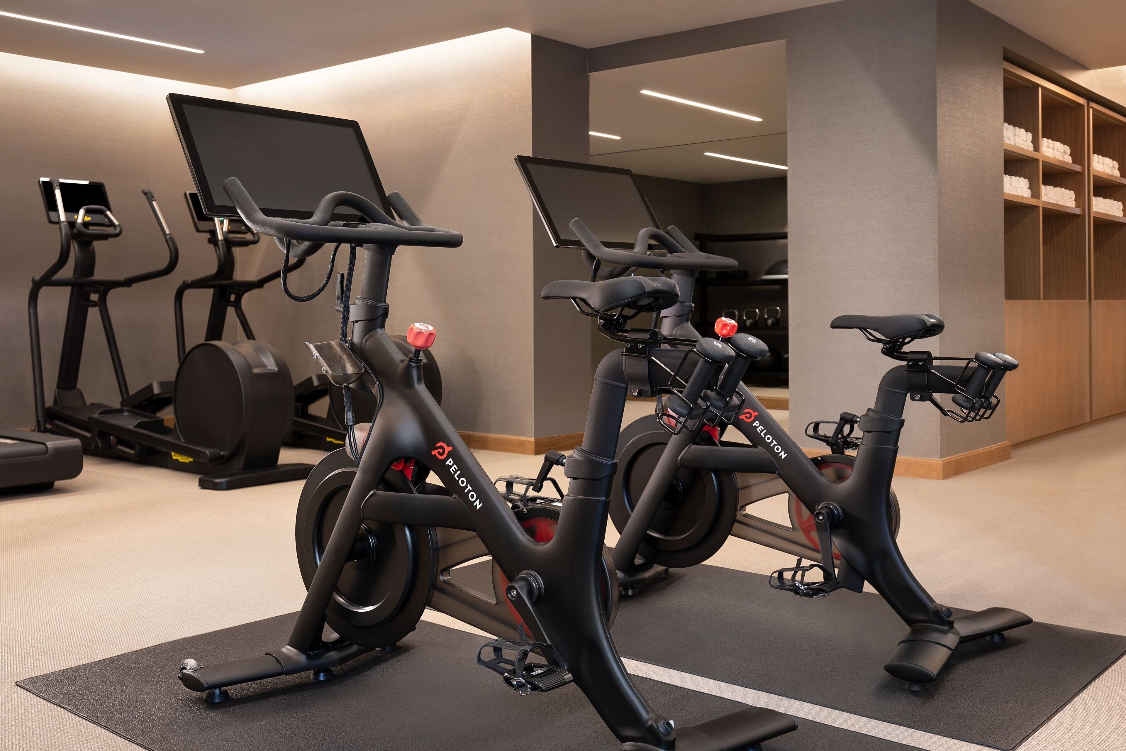 A gym with stationary bikes, treadmills, and a mirrored wall.