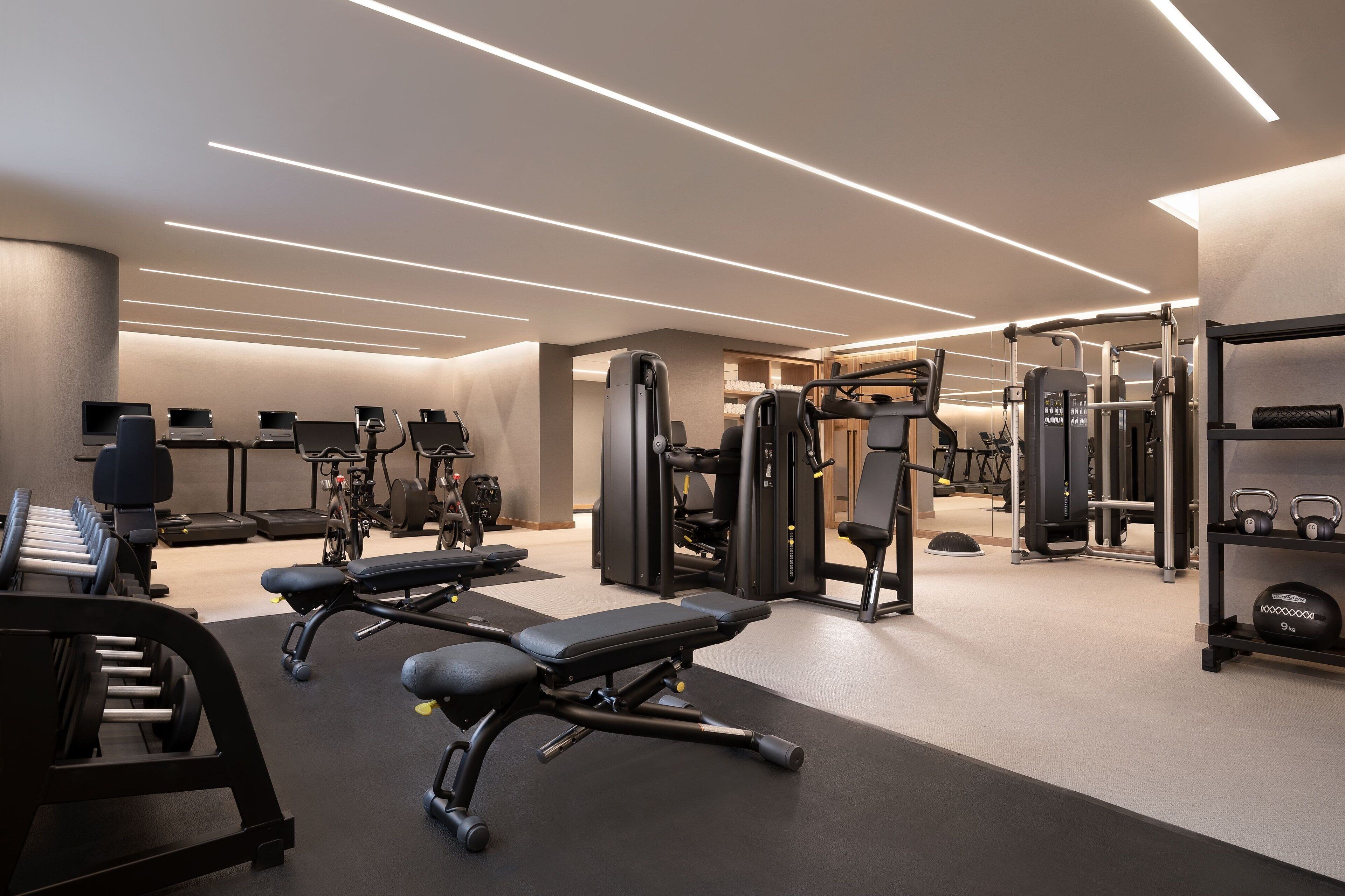 A modern gym with various exercise equipment, including treadmills, weight machines, and free weights.