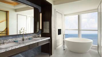 A modern bathroom with a large bathtub, a marble vanity, and a large mirror.