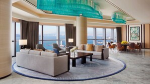 A spacious hotel lobby with a large seating area, a dining table, and a view of the cityscape. - The St. Regis Qingdao (Qingdao)