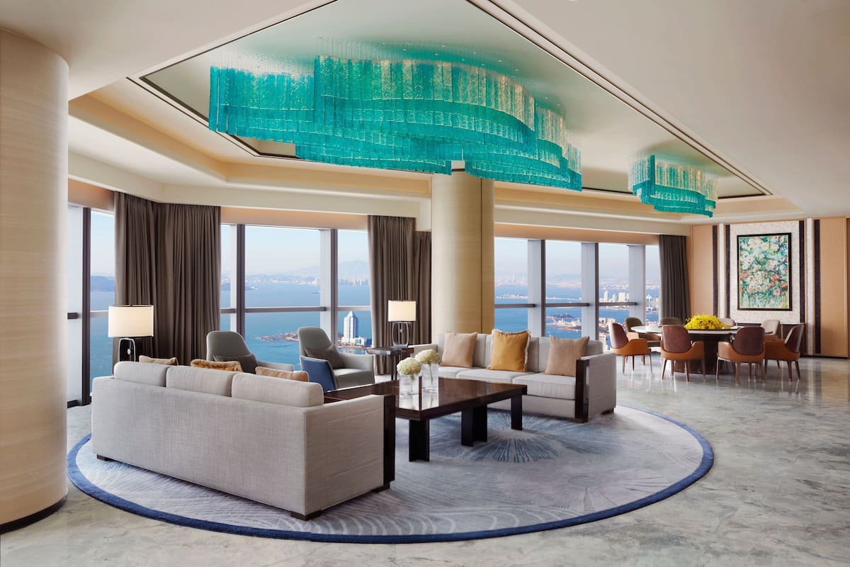 A spacious hotel lobby with a large seating area, a dining table, and a view of the cityscape.