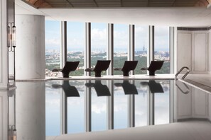 A modern indoor pool with a clear view of a cityscape through large windows. - The St. Regis Qingdao (Qingdao)