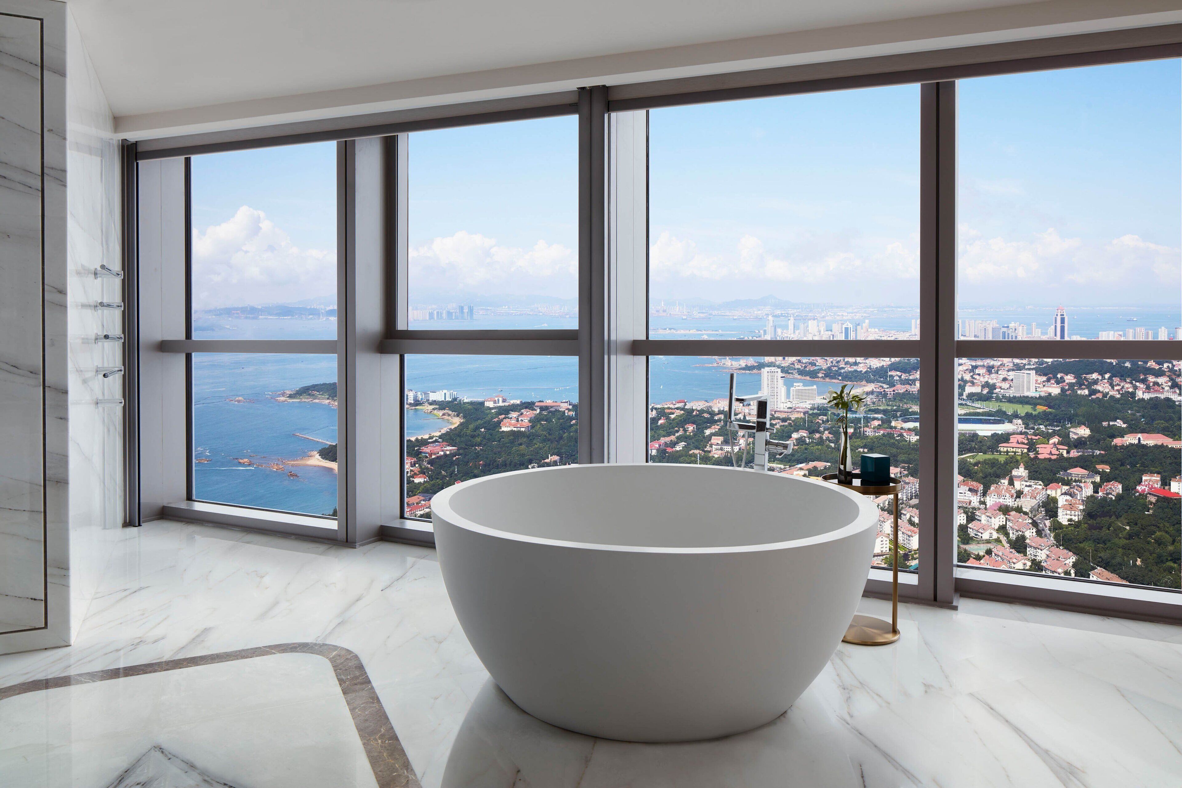 Une salle de bain moderne avec une grande baignoire, de grandes fenêtres et une vue sur la ville.
