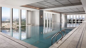 A modern indoor swimming pool with large windows offering city views. - The St. Regis Qingdao (Qingdao)