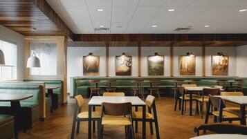 A restaurant interior with green booths, wooden tables, and chairs.