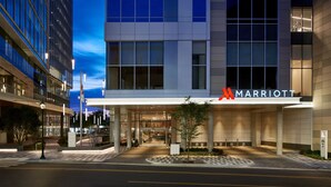 A Marriott hotel entrance with a modern design, large windows, and a well-lit facade.