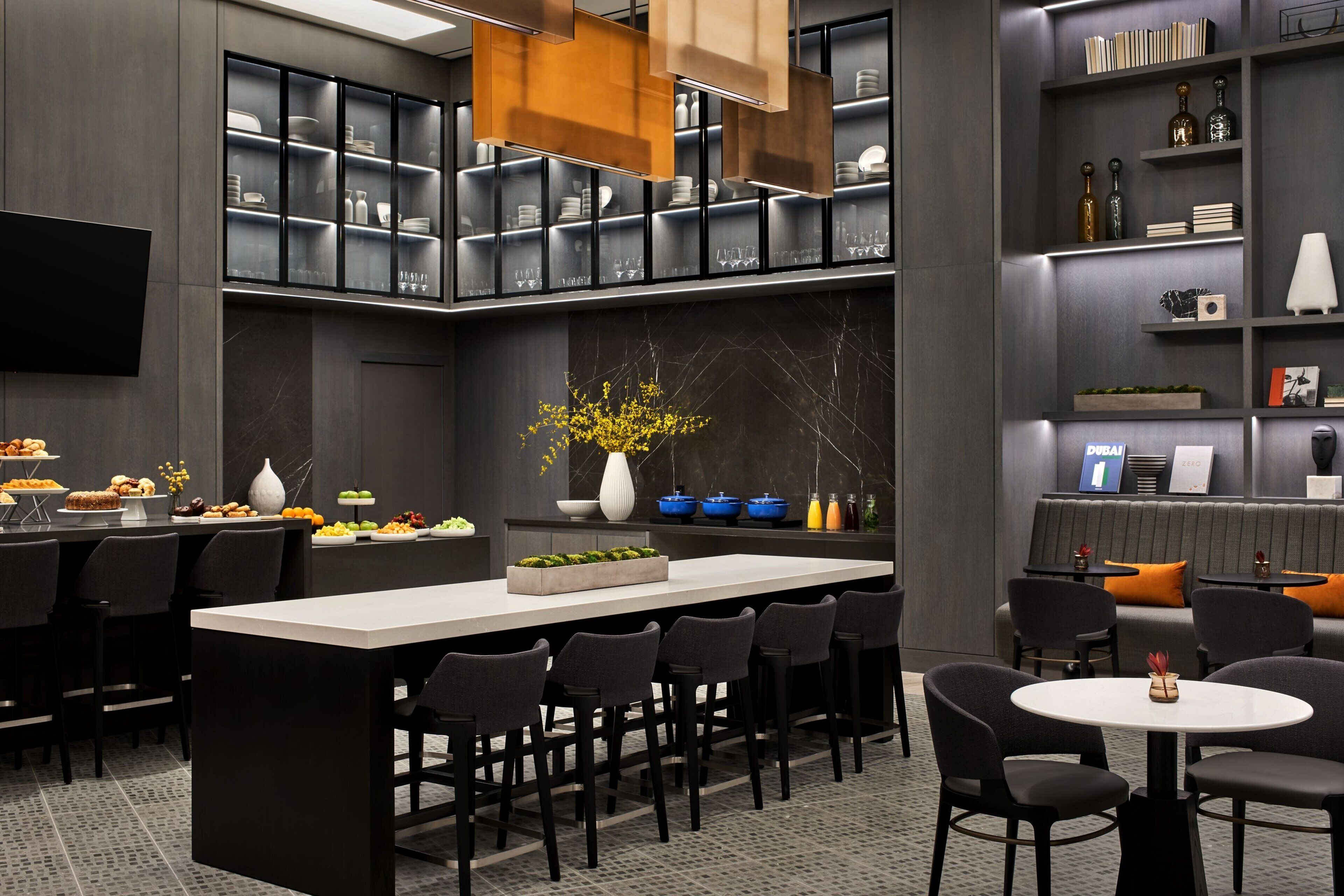 A modern kitchen with a central island, bar seating, and a dining area with chairs and tables.
