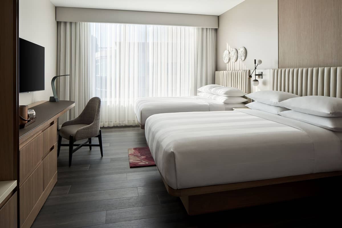 Een moderne hotelkamer met twee bedden, een televisie, een bureau en een stoel.