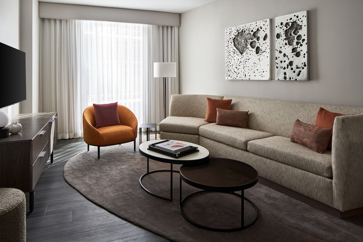 Een moderne woonkamer met een bank, fauteuil, salontafel en kunst aan de muur.