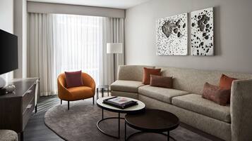 A modern living room with a sofa, armchair, coffee table, and artwork on the wall.