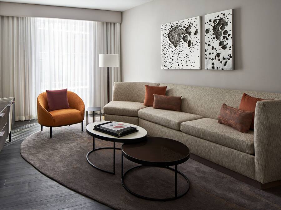 A modern living room with a sofa, armchair, coffee table, and artwork on the wall.