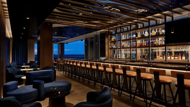 A bar area with seating and a view of the cityscape.