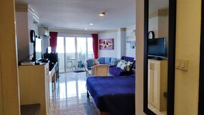 A hotel room with a bed, a TV, a desk, and a balcony with a chair. - Facing the sea with a clear view of Patong Bay (Patong)