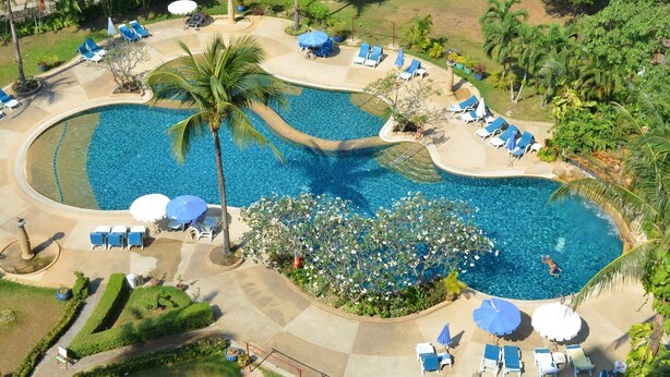 An aerial view of a resort with a large swimming pool, sun loungers, and palm trees. - Facing the sea with a clear view of Patong Bay (Patong)
