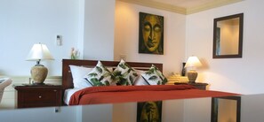 A hotel room with a bed, two bedside tables, a nightstand, a wall-mounted mirror, and a painting above the bed. - Facing the sea with a clear view of Patong Bay (Patong)