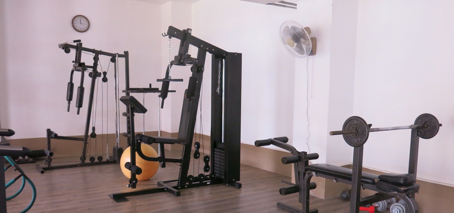 Une salle de sport équipée de divers appareils d’entraînement, notamment un banc de développé couché, un support à squats et un ballon lesté.