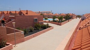 A residential area with terracotta-roofed buildings, a swimming pool, and a clear sky. - Spacious 3 bed/2 bath house, on a gated complex, Fibre Wifi. Two communal pools. (Antigua)