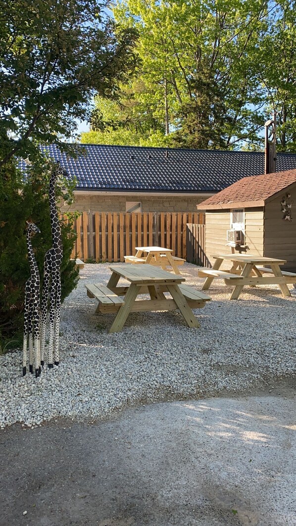 Ein Picknickbereich mit Holztischen und -bänken, umgeben von einem Kiesweg und einem Holzzaun.