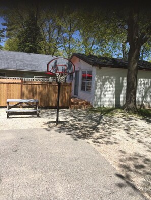 Enjoy outdoor games and relaxation in the shaded backyard with a basketball hoop and seating area.