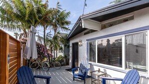 Un patio con sillas Adirondack azules, una bicicleta y una mesita.