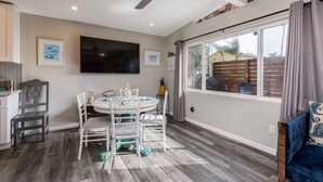 Una cocina moderna con comedor, ventilador de techo y un ventanal con cortinas.