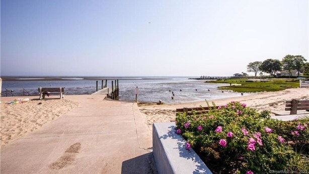 A beach with a concrete walkway, benches, and a flower bed. - Steps to the Beach, Cozy Year Round Cottage 🐾 Pet Friendly (Old Saybrook)