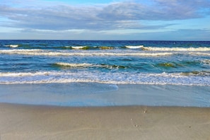 Una playa con olas, arena y cielo despejado.