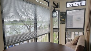Ein Essbereich mit einem runden Tisch, einem 'RELAX'-Schild und Blick ins Freie durch große Fenster.