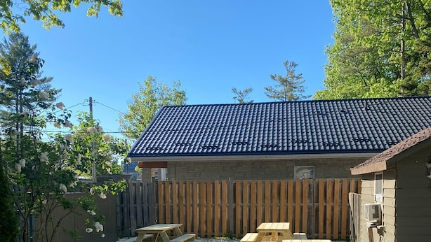 Un patio con mesas de picnic y un pequeño edificio con techo de tejas.