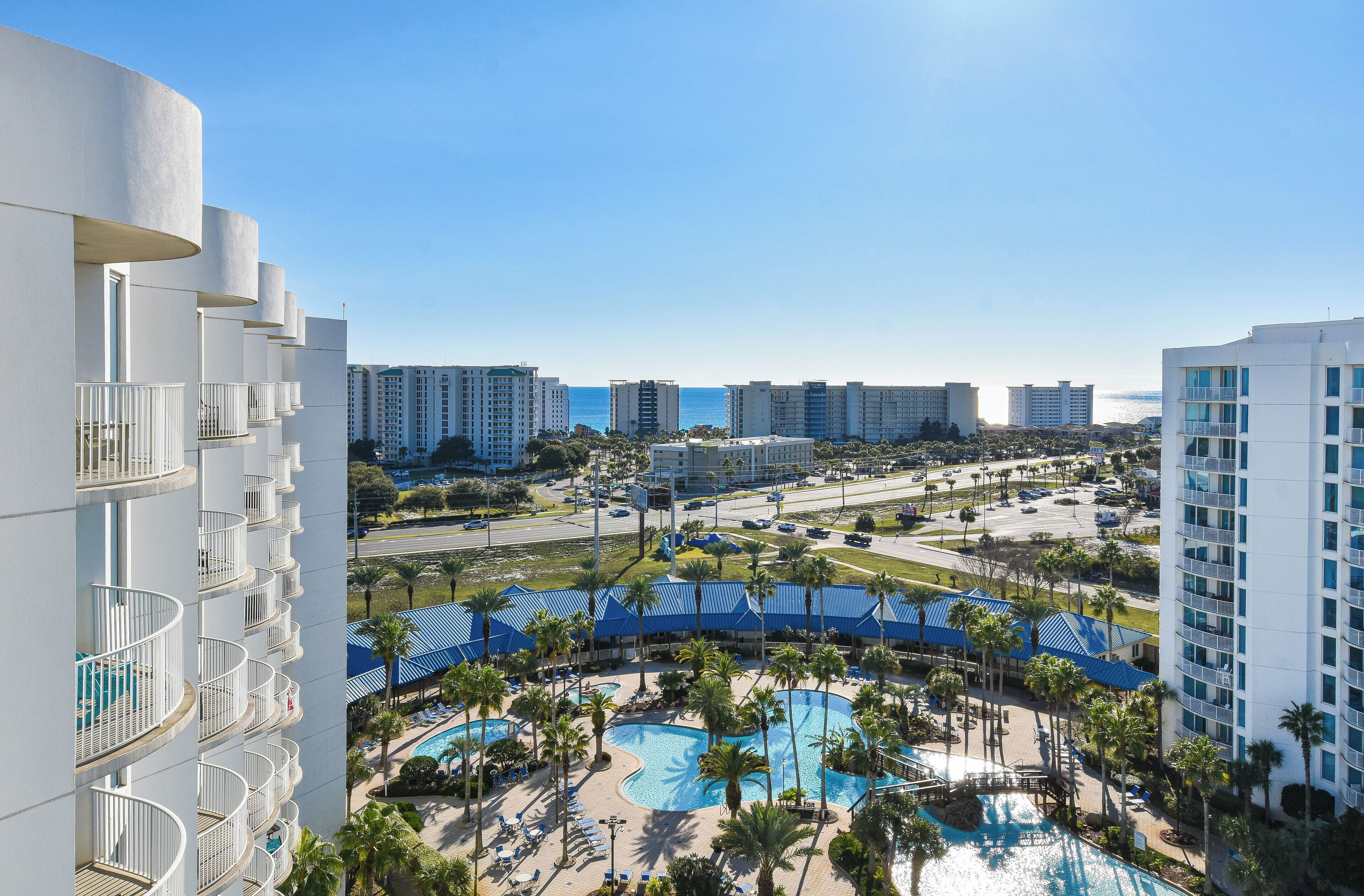 A resort with a large pool area, multiple balconies, and a view of the surrounding cityscape.