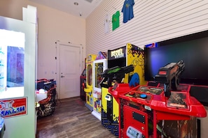 A room with arcade games, a door, and a wall-mounted TV. - 6th Floor condo at The Palms of Destin with Seasonal Beach Shuttle! (Destin)