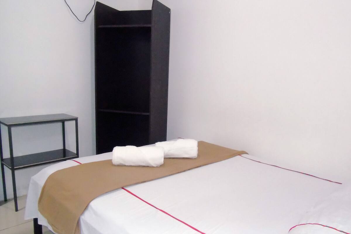 A hotel room with a bed, a small table, and a wardrobe.