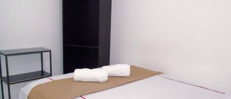 A hotel room with a bed, a small table, and a wardrobe.
