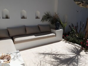 Relax in this serene outdoor seating area with a comfortable sofa and lush greenery.