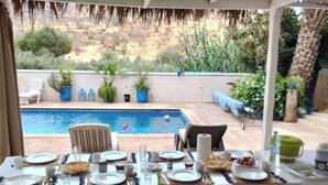 Zona pranzo con vista piscina, posti a sedere all'aperto e piante in vaso.