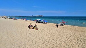 A beach with umbrellas and beachgoers.