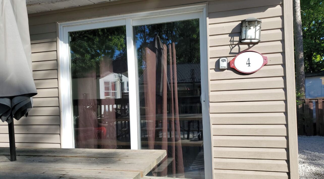 Une maison avec une porte-fenêtre coulissante, une enseigne portant le numéro 4 et une lanterne fixée au mur.