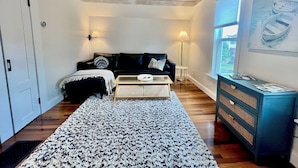 Un salon chaleureux avec un canapé en cuir noir, un tapis à motifs et une table basse en bois.